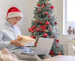 Jeune homme ouvrant un cadeau près du sapin