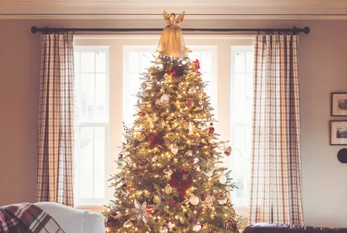 Grand sapin de Noël décoré devant la fenêtre d'un salon